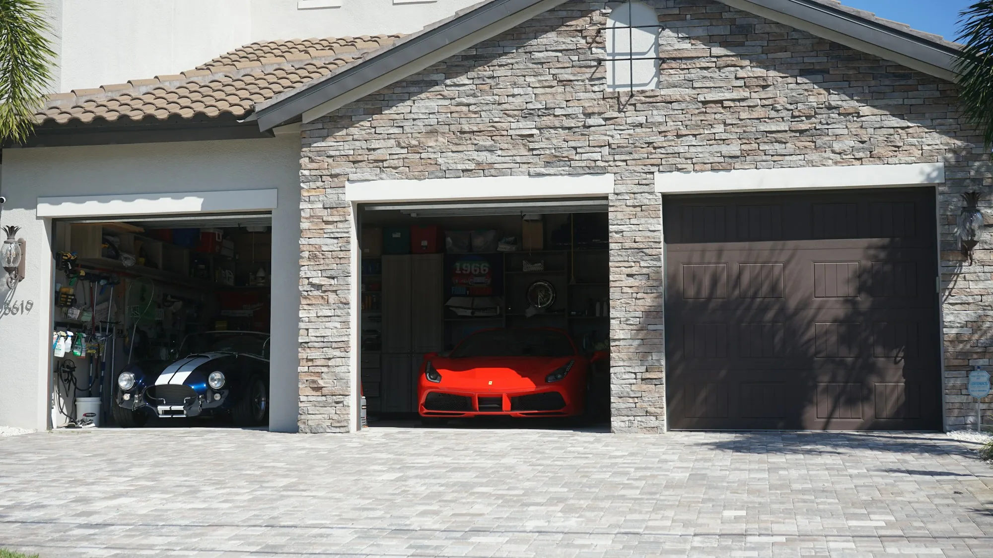 Stone-front home with an open garage and a car inside