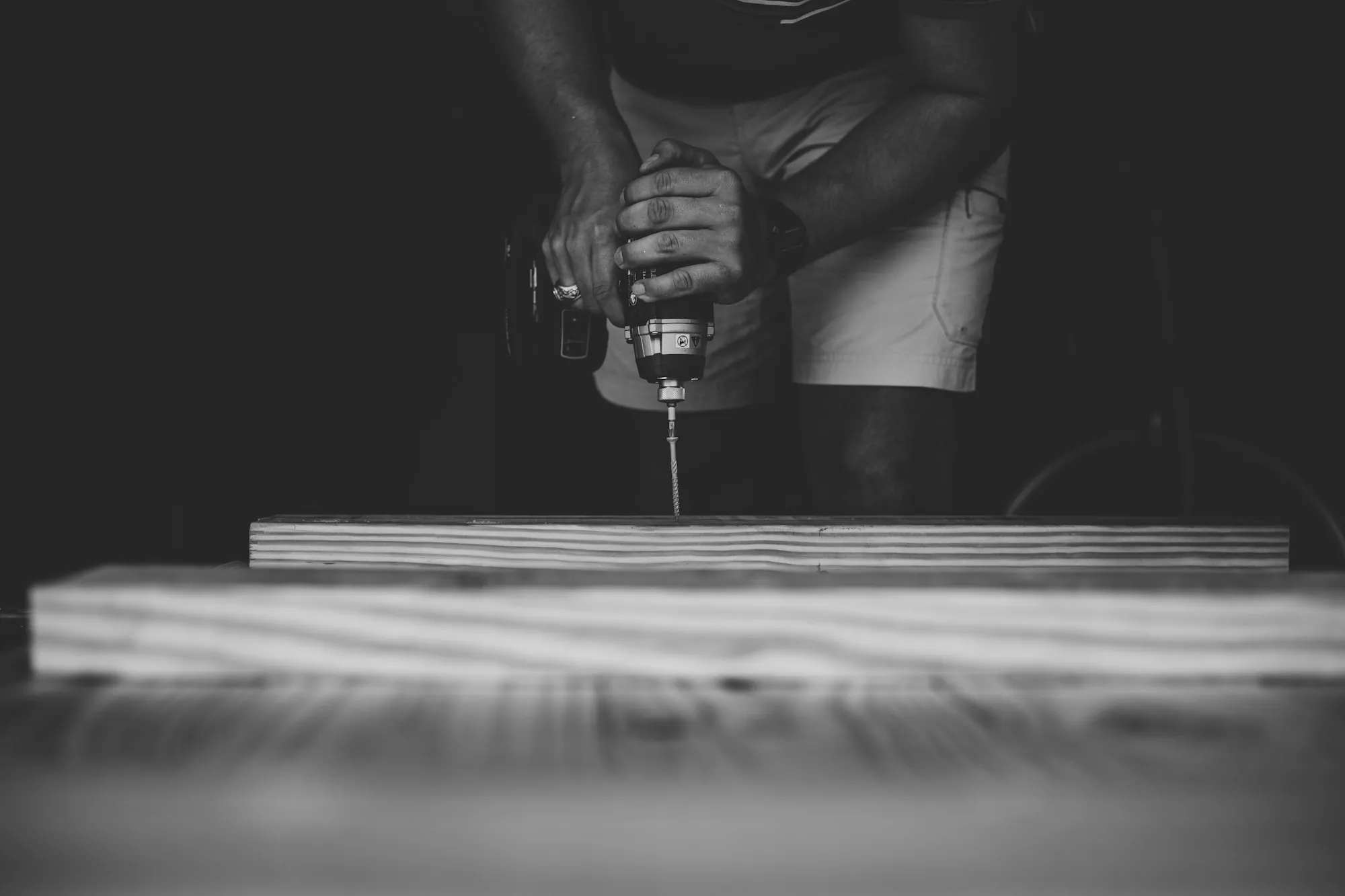 Black and white photo of a drill boring into a board